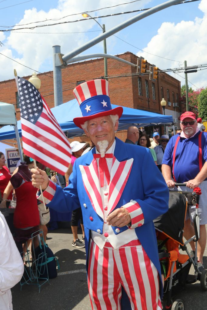 man dressed as uncle sam holding an american flag at a parade or celebration
